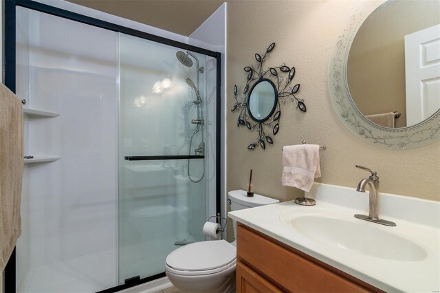bathroom with vanity, a shower stall, and toilet