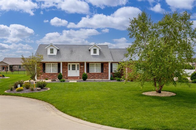 cape cod home with brick siding and a front yard