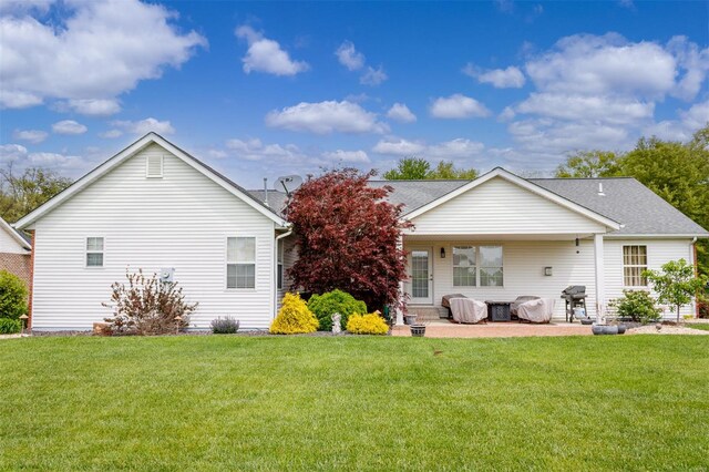 rear view of property with a lawn, a shingled roof, and a patio