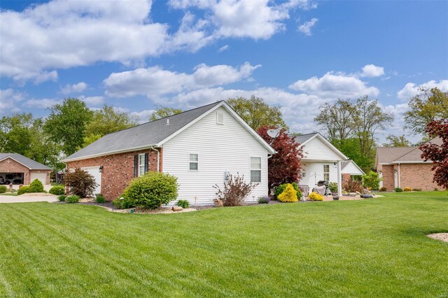 view of side of property with a lawn, a garage, and brick siding