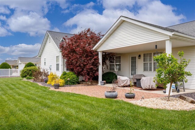 view of property exterior with a lawn, a shingled roof, a patio area, and fence