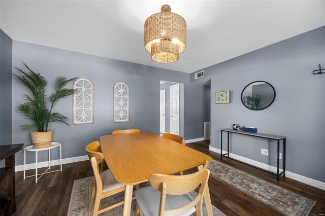 dining room featuring baseboards, visible vents, wood finished floors, and a notable chandelier