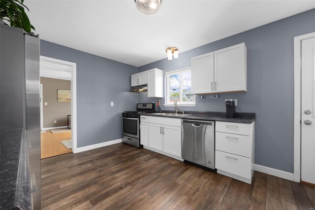 kitchen with a sink, dark wood-style flooring, under cabinet range hood, and stainless steel appliances