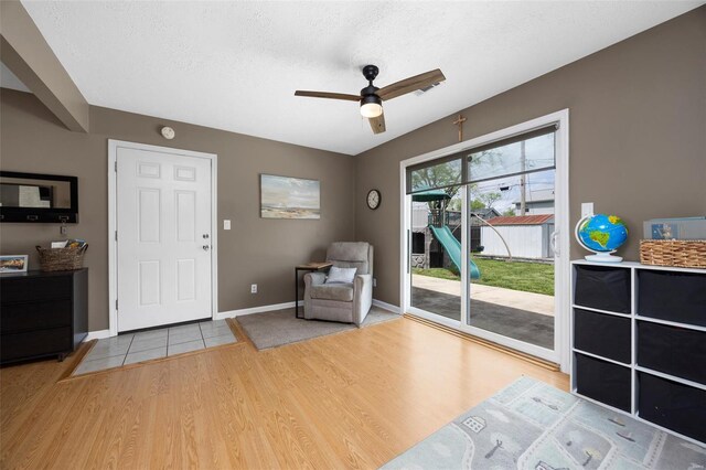living area with baseboards, a ceiling fan, and wood finished floors