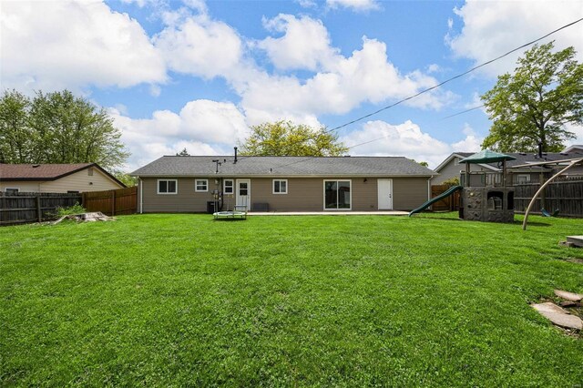 rear view of property featuring a playground, a patio, a lawn, and a fenced backyard