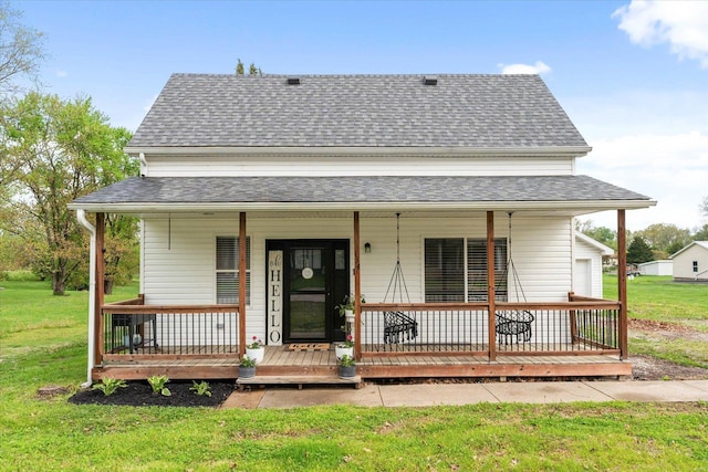 view of front of home with covered porch, a shingled roof, and a front yard