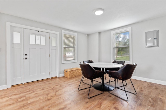 dining space with light wood-style floors, baseboards, and electric panel