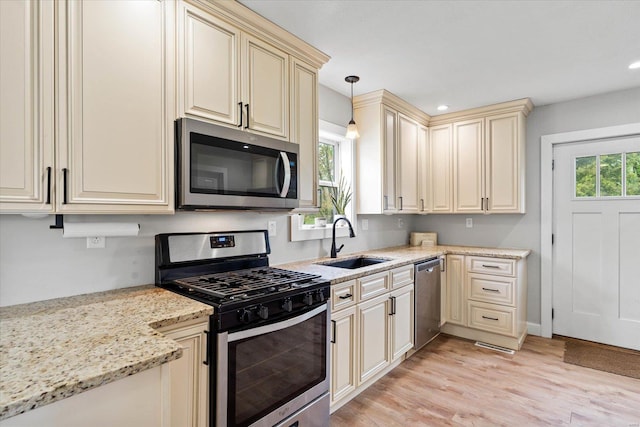 kitchen with light wood-style floors, a sink, appliances with stainless steel finishes, and cream cabinetry