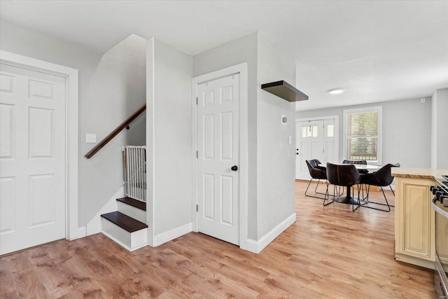 foyer with stairway, baseboards, and light wood finished floors