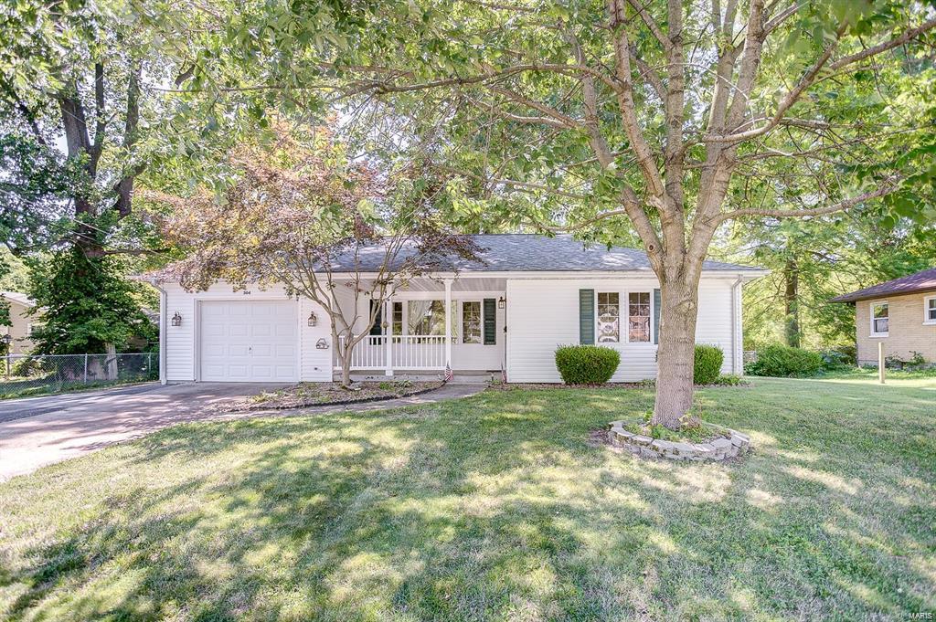 view of front facade with fence, a garage, a front yard, covered porch, and driveway