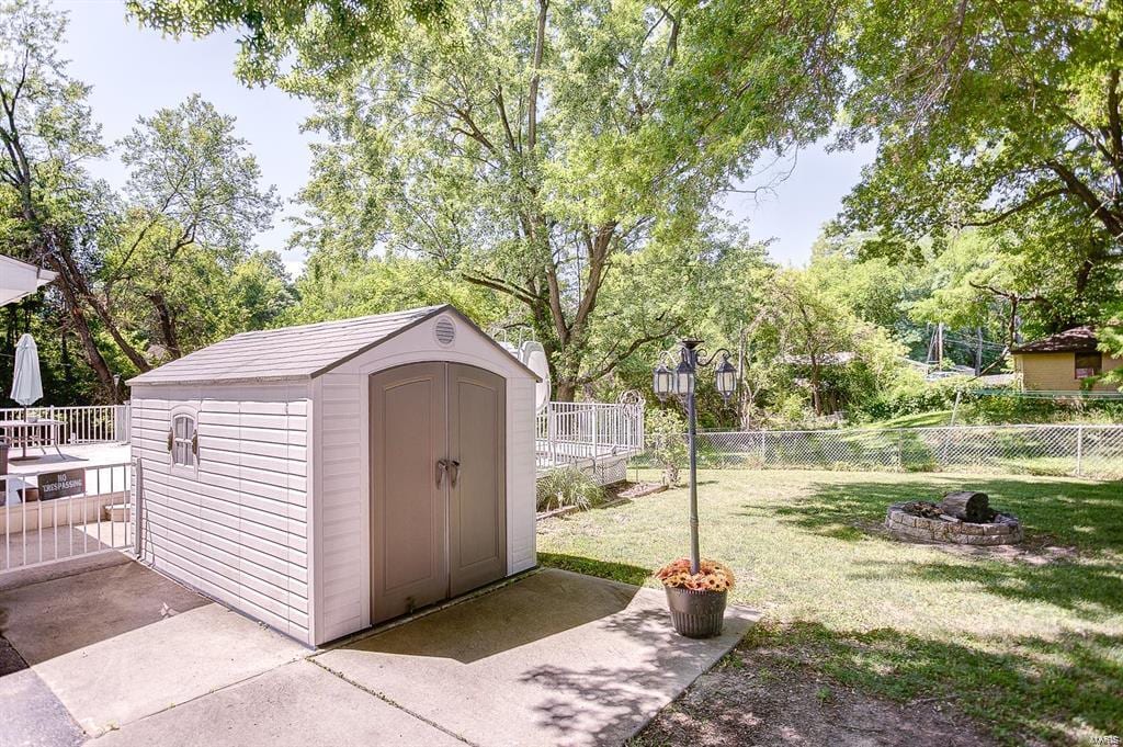 view of shed with a fenced backyard and a fire pit
