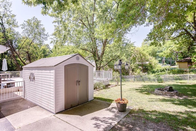 view of shed with a fenced backyard and a fire pit