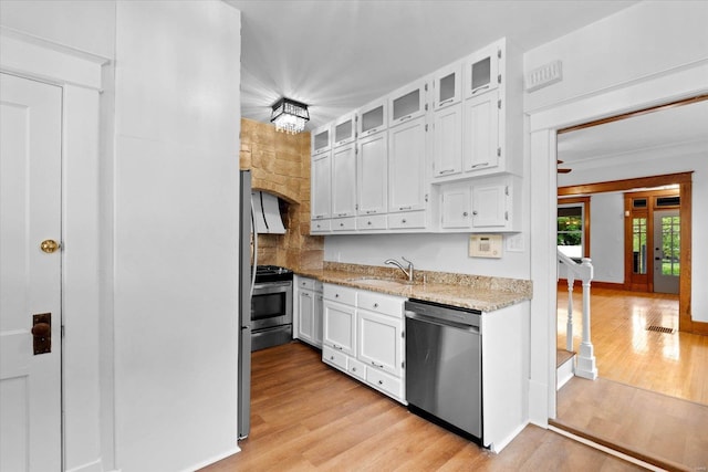 kitchen with stainless steel appliances, white cabinets, light wood-type flooring, and a sink