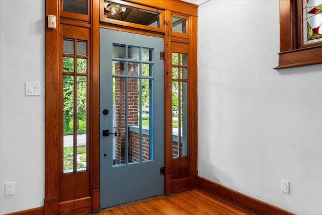 doorway featuring baseboards and wood finished floors