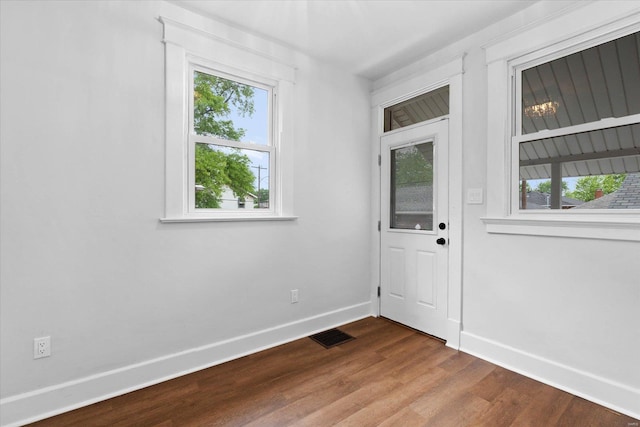 doorway with baseboards, visible vents, and wood finished floors