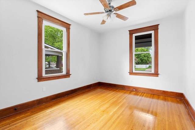 spare room featuring baseboards, a healthy amount of sunlight, and hardwood / wood-style flooring
