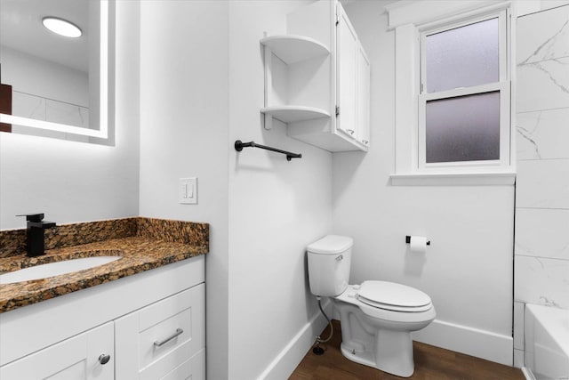 bathroom with toilet, baseboards, vanity, and wood finished floors