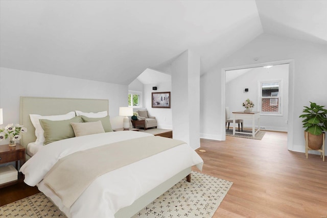 bedroom with baseboards, light wood-style flooring, and lofted ceiling
