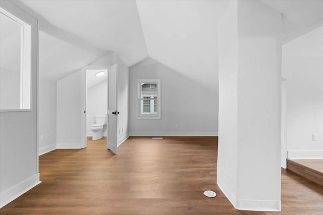 additional living space featuring baseboards, wood finished floors, and lofted ceiling