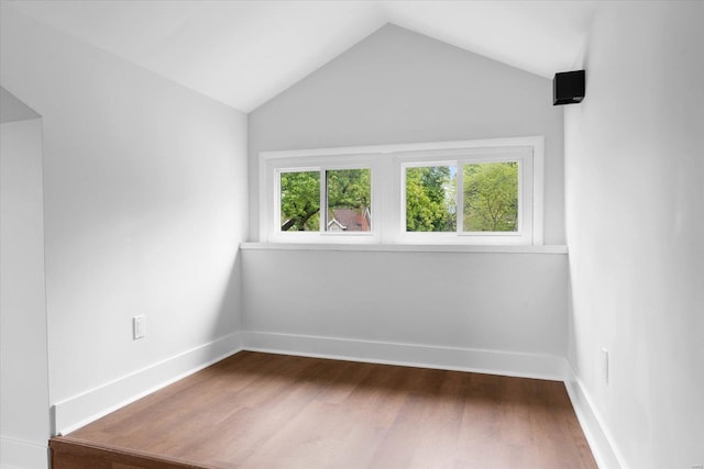 unfurnished room featuring baseboards, dark wood-type flooring, and vaulted ceiling