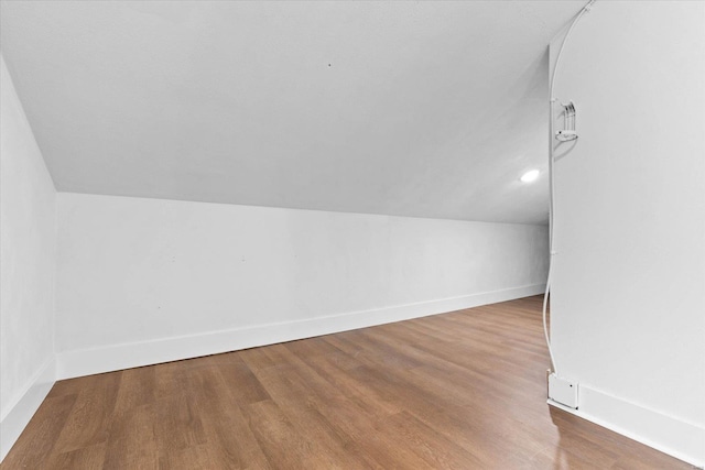 additional living space with baseboards, wood finished floors, and lofted ceiling