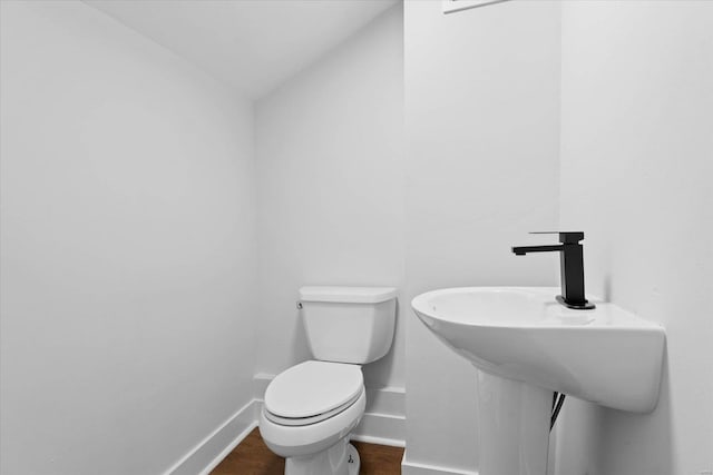 bathroom featuring wood finished floors, baseboards, toilet, and a sink