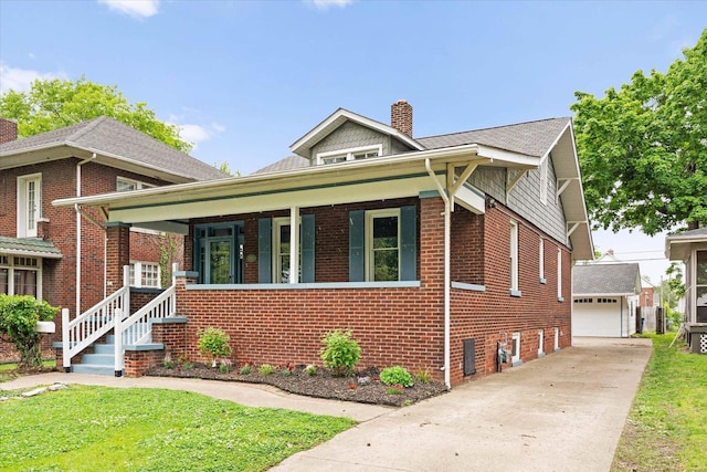 bungalow-style home featuring a chimney, an outdoor structure, brick siding, and a detached garage