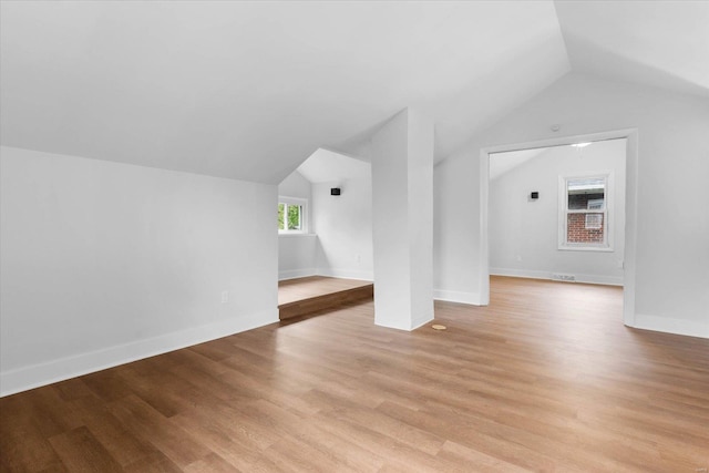 additional living space with light wood-type flooring, vaulted ceiling, and baseboards