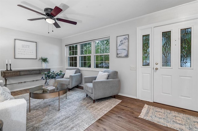 living room with crown molding, baseboards, a ceiling fan, and wood finished floors