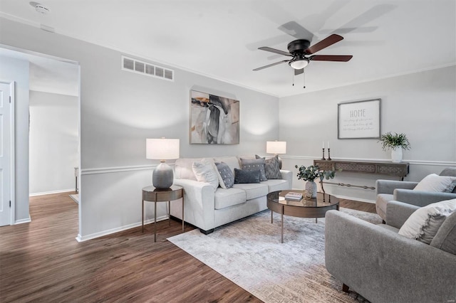 living room with visible vents, crown molding, wood finished floors, baseboards, and ceiling fan