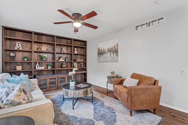 living area with baseboards, visible vents, ceiling fan, and wood finished floors