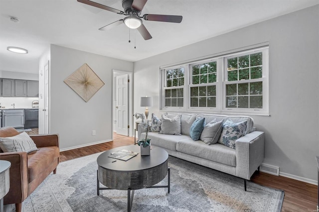 living room featuring ceiling fan, baseboards, visible vents, and wood finished floors