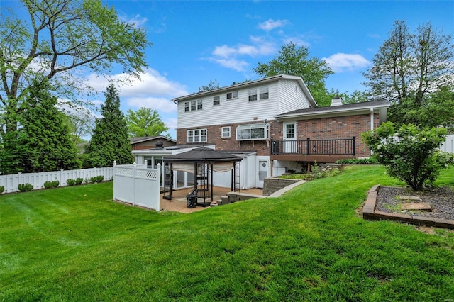 back of property with fence, a wooden deck, a lawn, and brick siding
