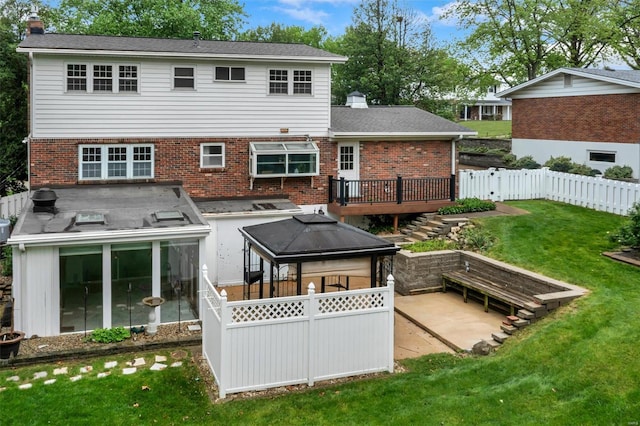 back of property featuring a wooden deck, fence, a chimney, brick siding, and a patio area