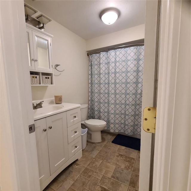 full bathroom featuring toilet, a shower with curtain, stone finish flooring, and vanity