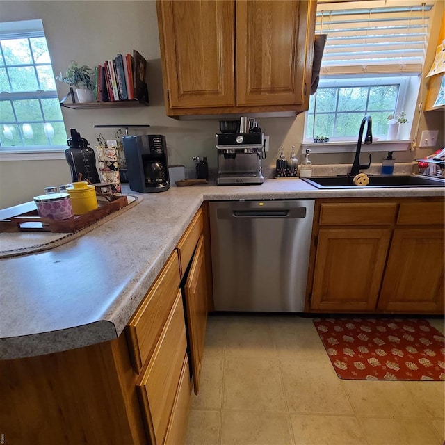 kitchen featuring stainless steel dishwasher, a sink, brown cabinets, and light countertops