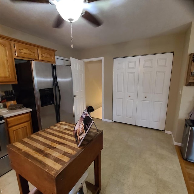 kitchen with a ceiling fan, stainless steel refrigerator with ice dispenser, light countertops, baseboards, and light floors