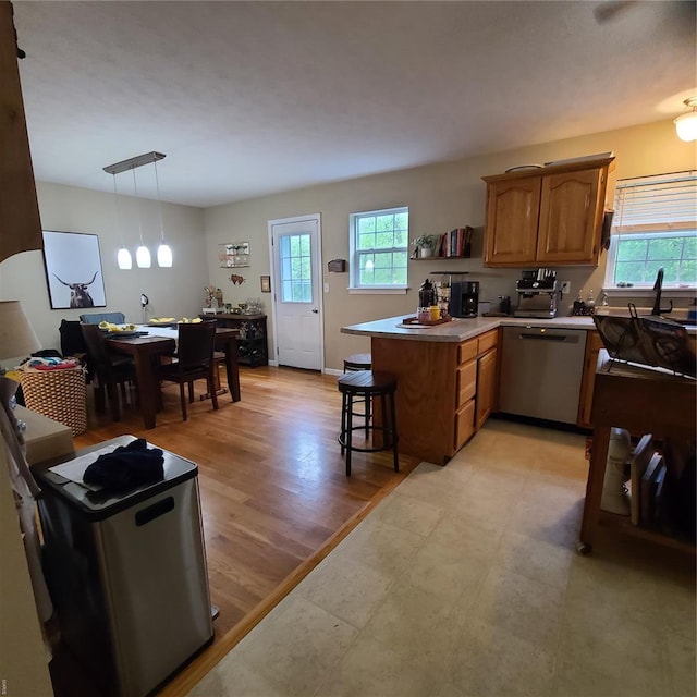 kitchen featuring a healthy amount of sunlight, hanging light fixtures, stainless steel dishwasher, and a peninsula