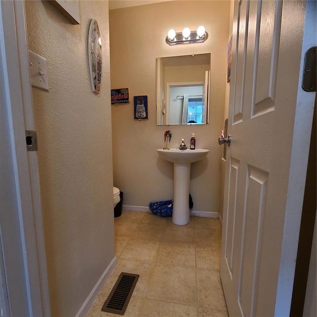 bathroom featuring baseboards, tile patterned floors, toilet, and visible vents