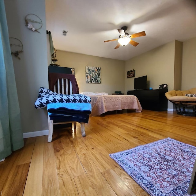 bedroom featuring ceiling fan, visible vents, baseboards, and light wood finished floors