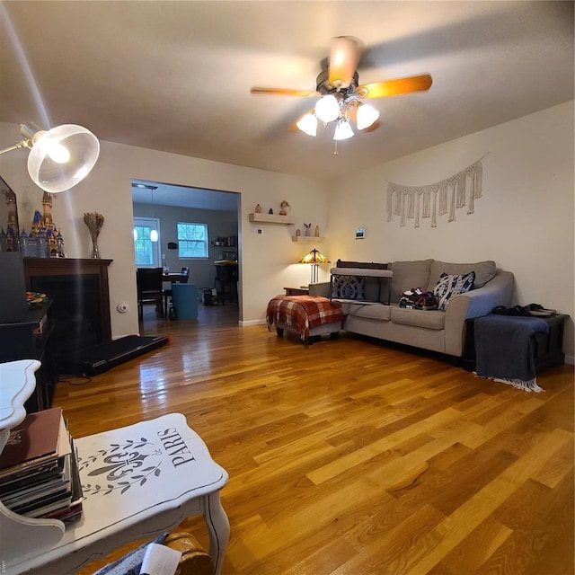 living area with light wood-type flooring and a ceiling fan