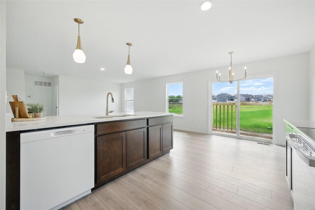 kitchen with a sink, light countertops, dark brown cabinetry, and white appliances