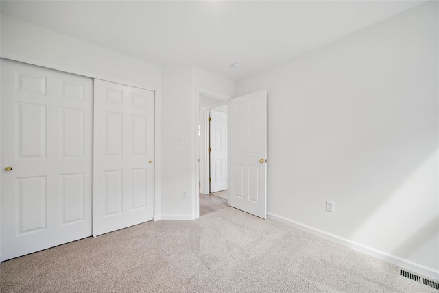 unfurnished bedroom with carpet flooring, baseboards, visible vents, and a closet