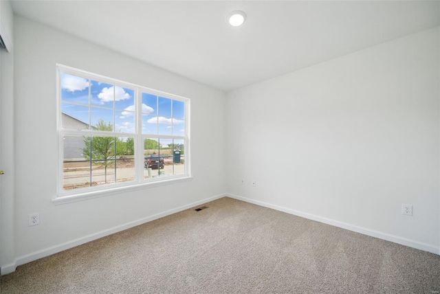 spare room featuring carpet floors, baseboards, and visible vents