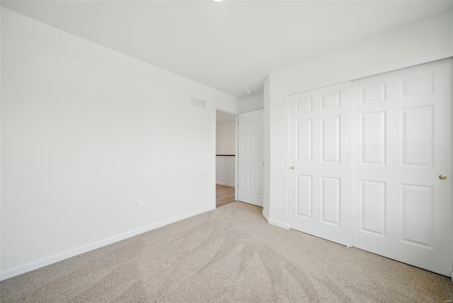 unfurnished bedroom with visible vents, carpet flooring, baseboards, and a closet