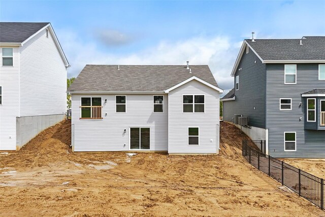 rear view of property with fence, central air condition unit, and a shingled roof