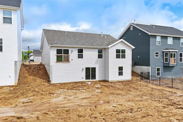 back of property featuring fence and a shingled roof