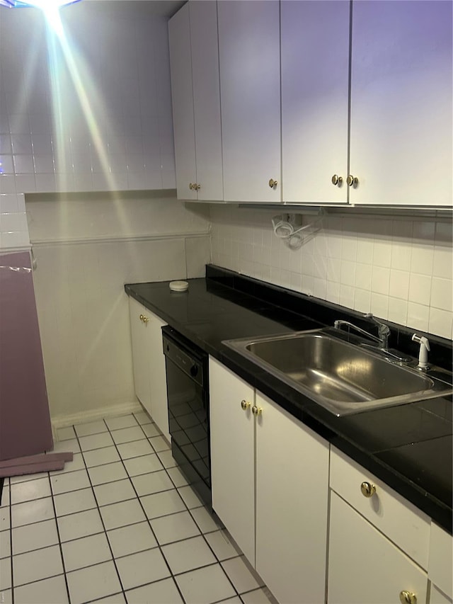 kitchen with a sink, dark countertops, black dishwasher, white cabinetry, and tasteful backsplash