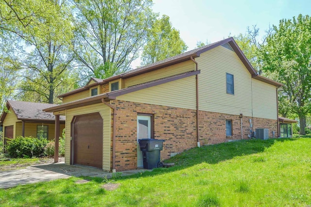 view of property exterior featuring brick siding, a garage, central AC unit, a yard, and driveway