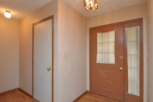 foyer with baseboards, light wood-style flooring, and a notable chandelier